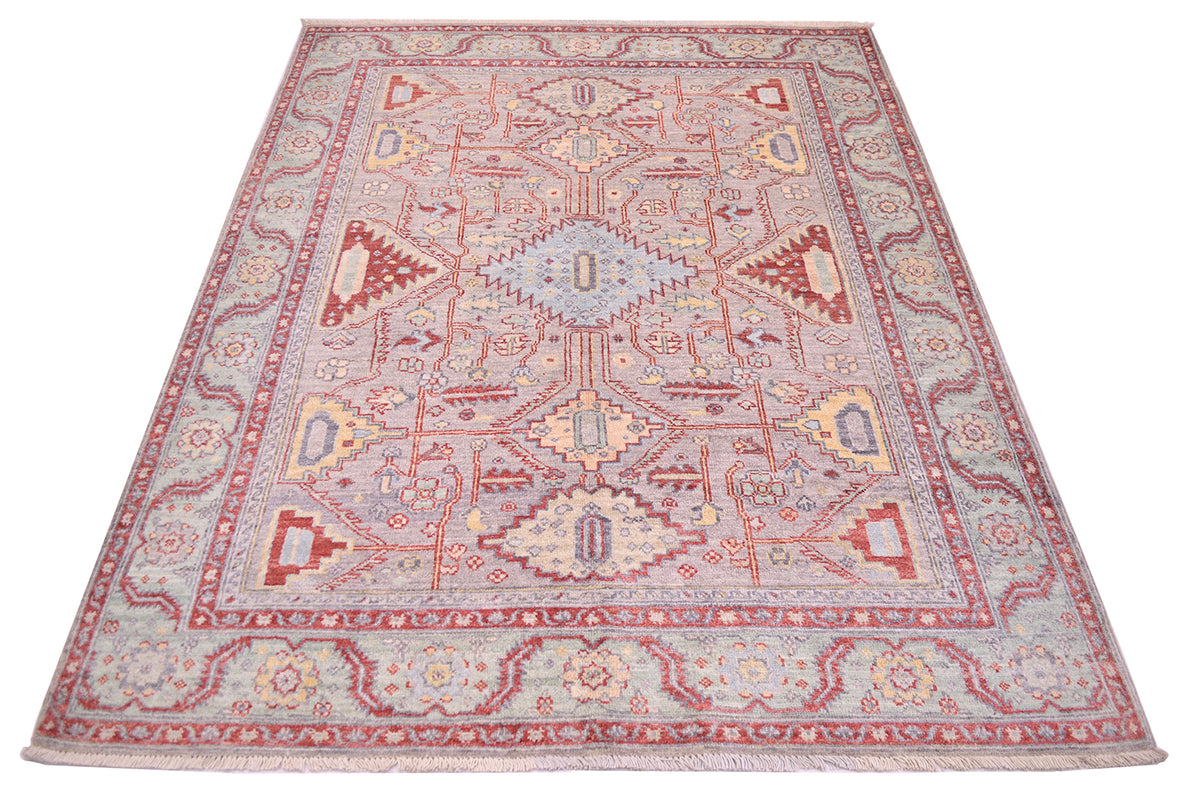 Geometricised floral motifs typify this handmade Afghan Serapi design rug with main field colour of soft grey with elemetns of yellow gold, soft green , light blue and light rust reds.