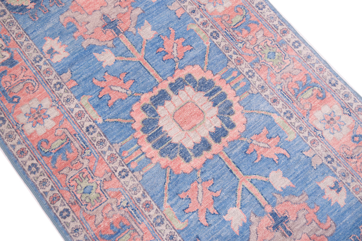 Close detail of handknotted rug with pure wool pile with characteristic lobed medallion with radiating appendages of Serapi Carpet design. Stylized cloudband border with pink background. 