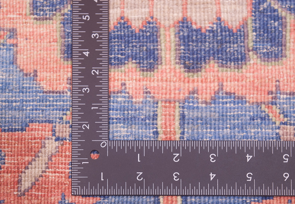 Reverse of runner rug showing knotting and variety of pleasing hues in  coral pink, blue and cream. 