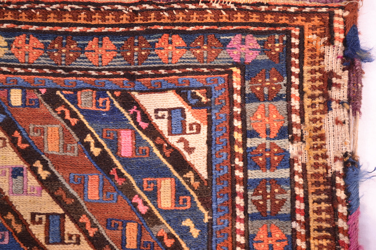 Antique khorjin rug corner close-up with multicolor border and diagonal stripe field