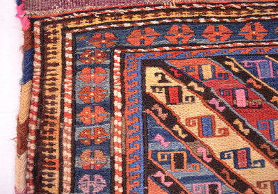 Antique khorjin rug corner close-up with diamond accents and blue rust border