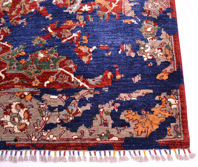 A close-up of a handmade Modern Sickle-Leaf carpet showing its detailed woven pattern, deep navy blue field, red border, and multicolored fringe.