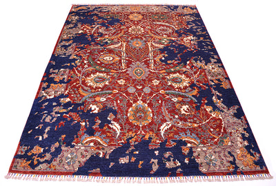 A traditional oriental area rug with an intricate floral and medallion pattern, featuring a deep navy blue field, red and orange central motifs, and cream and beige accents, finished with white fringe on the bottom edge.