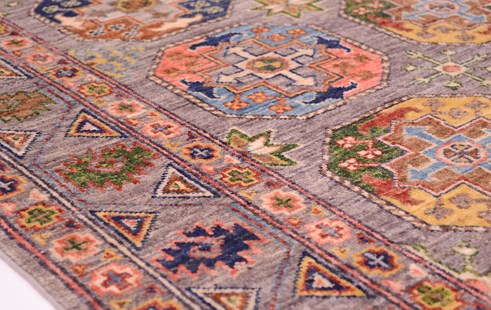 Close up detail of border and field of afghan handmade sultani rug with multicolour geometric features and guls with a soft grey field.