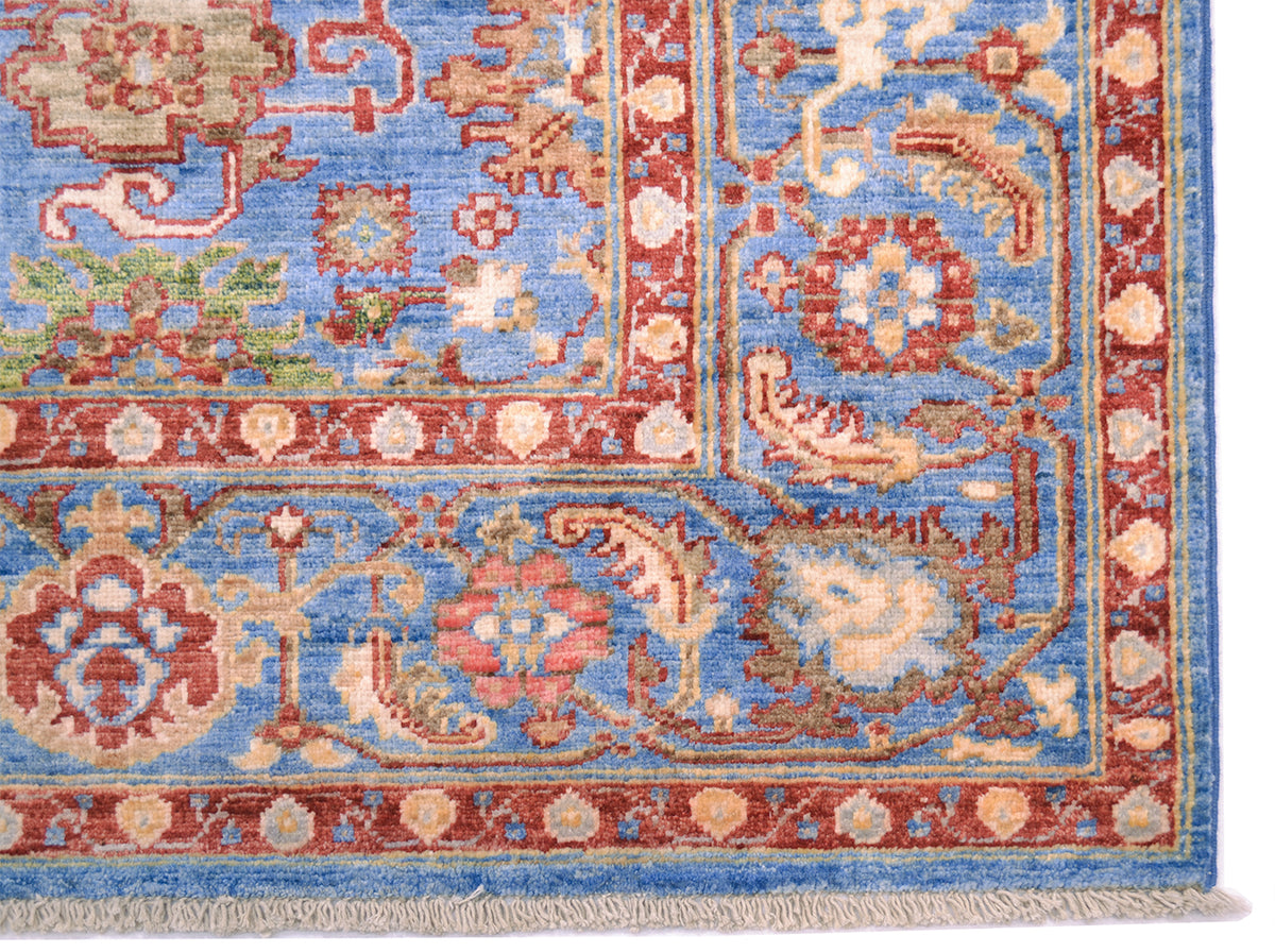 Detail showing corner and part of field of blue and red Sultanabad carpet with cloudband border and furling leaves with alternating palmettes and rosettes. Cotton warp fringes for firm foundation of pure wool pile. 