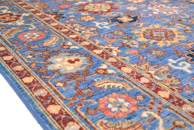 Detail of border of blue and red Sultanabad rug with blue and coral pink rosettes with cream and light gold outlining. Handknotted in Afghanistan with handspun wool.