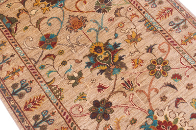 Close up detail of main field of Sultani rug with neutral beige gold field colour filled with floral motifs with turquoise, deep greens, greens and rusts and golds.