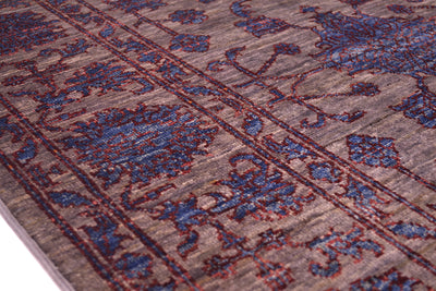 Close up and detail of border of handmade rug wirh multiple floral motifs in main field and border wirh ornate blue blossomheads with rich chestnut contrasting outling and grey/brown background.
