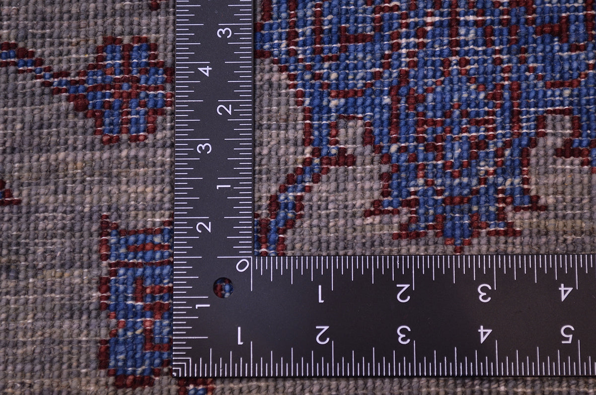 Reverse of handmade rug showing fine knotting and back of individual knots in greys, blue and chestnut brown-red.