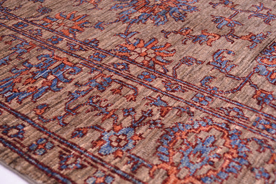 Detail of floral border of handmade rug with traditional Persian floral design with dual hued detailing and neutral grey brown background.