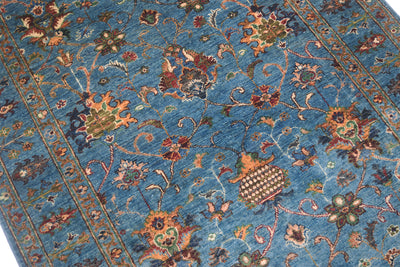 Detail view and close up of main decorative field of blue handmade rug with Sultani design with interconnecting palmettes and flowerheads as well as blossoms and curling vines.