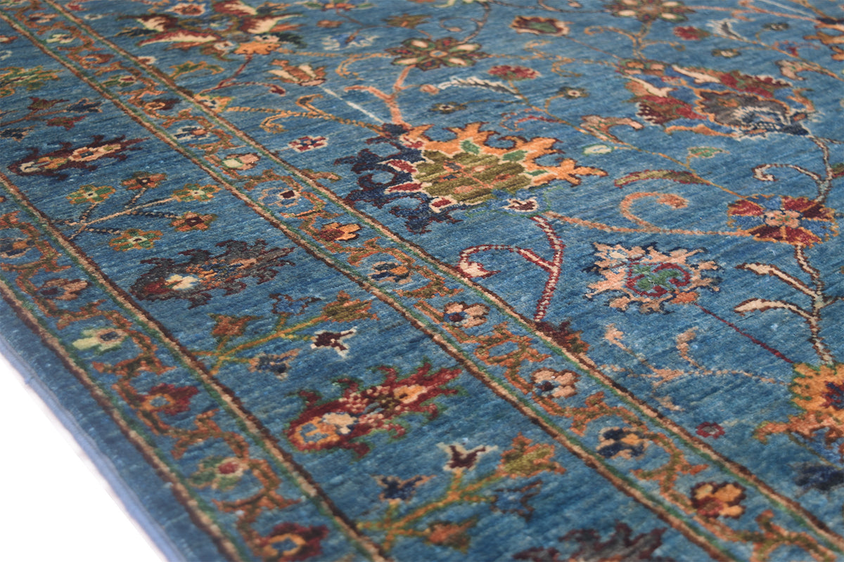 Detail of border of blue sultani rug with an array of floral moifs and blue main ground and all over floral design.