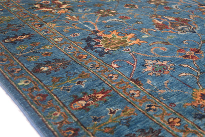 Detail of border of blue sultani rug with an array of floral moifs and blue main ground and all over floral design.