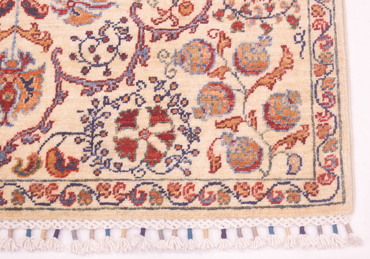 Rug corner close-up showing multicolor motifs on cream and white tassel fringe