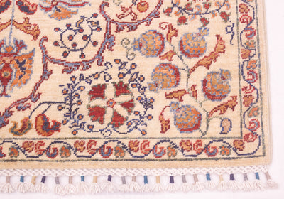Rug corner close-up showing multicolor motifs on cream and white tassel fringe