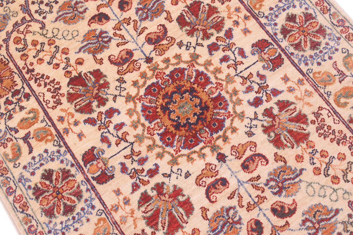 Rug close-up with central red medallion and dense multicolor floral details on cream