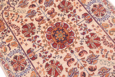 Rug close-up with central red medallion and dense multicolor floral details on cream