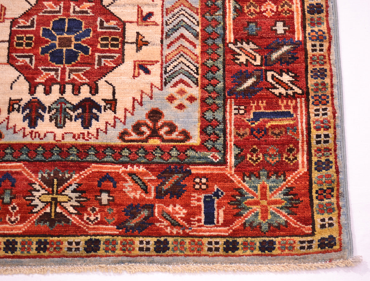 A close-up of a traditional handwoven antique finish Afghan runner corner, showing detailed geometric and floral patterns in red, beige, blue, and green.