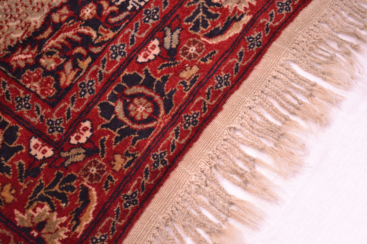Old Belouch-Tavusi rug side edge close-up with dark red pattern and pale pink fringes.