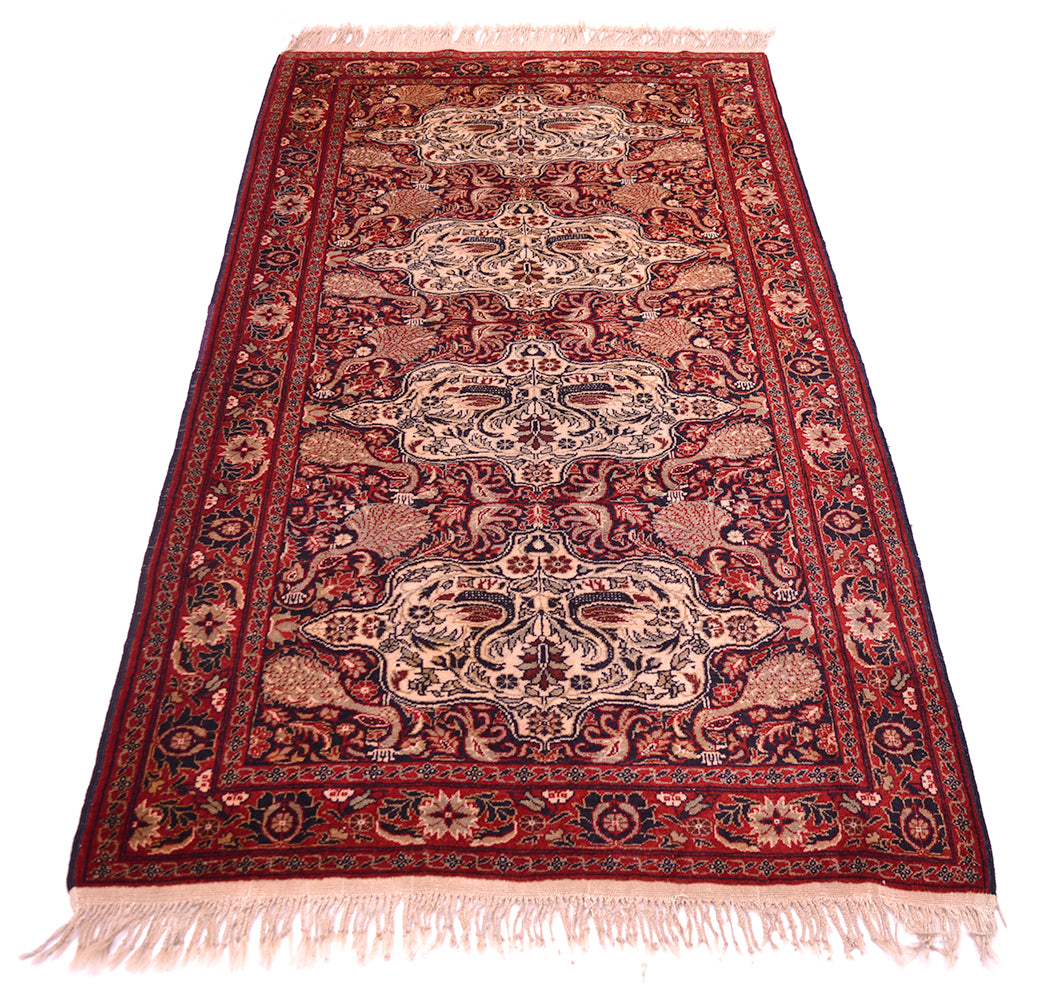 Old Belouch-Tavusi rug front view with dark red field, cream ornamental panels, pink fringe.