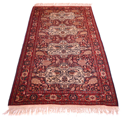 Old Belouch-Tavusi rug front view with dark red field, cream ornamental panels, pink fringe.