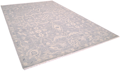 A rectangular tonal  area rug with an intricate traditional pattern in muted grey and beige tones, shown from an elevated perspective against a white background.