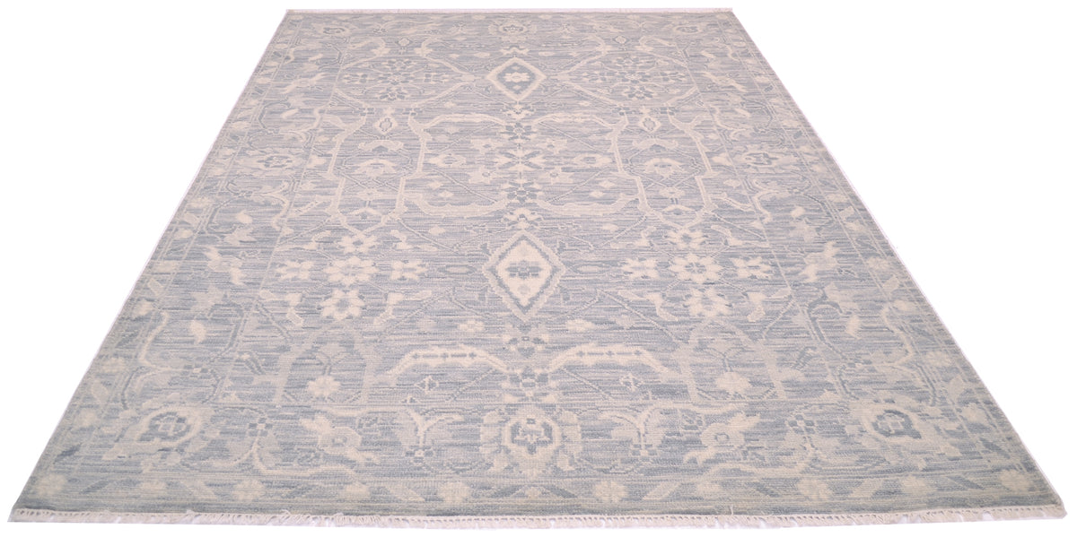 A rectangular area rug with a traditional floral geometric pattern in light grey and cream, shown from a top-down perspective on a white background.