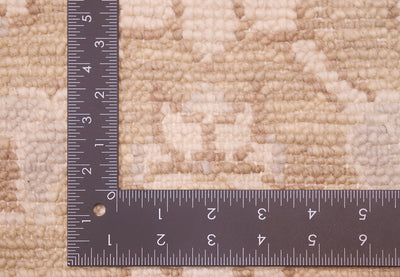 Close-up of a beige and cream patterned rug with a ruler placed along the corner to show scale