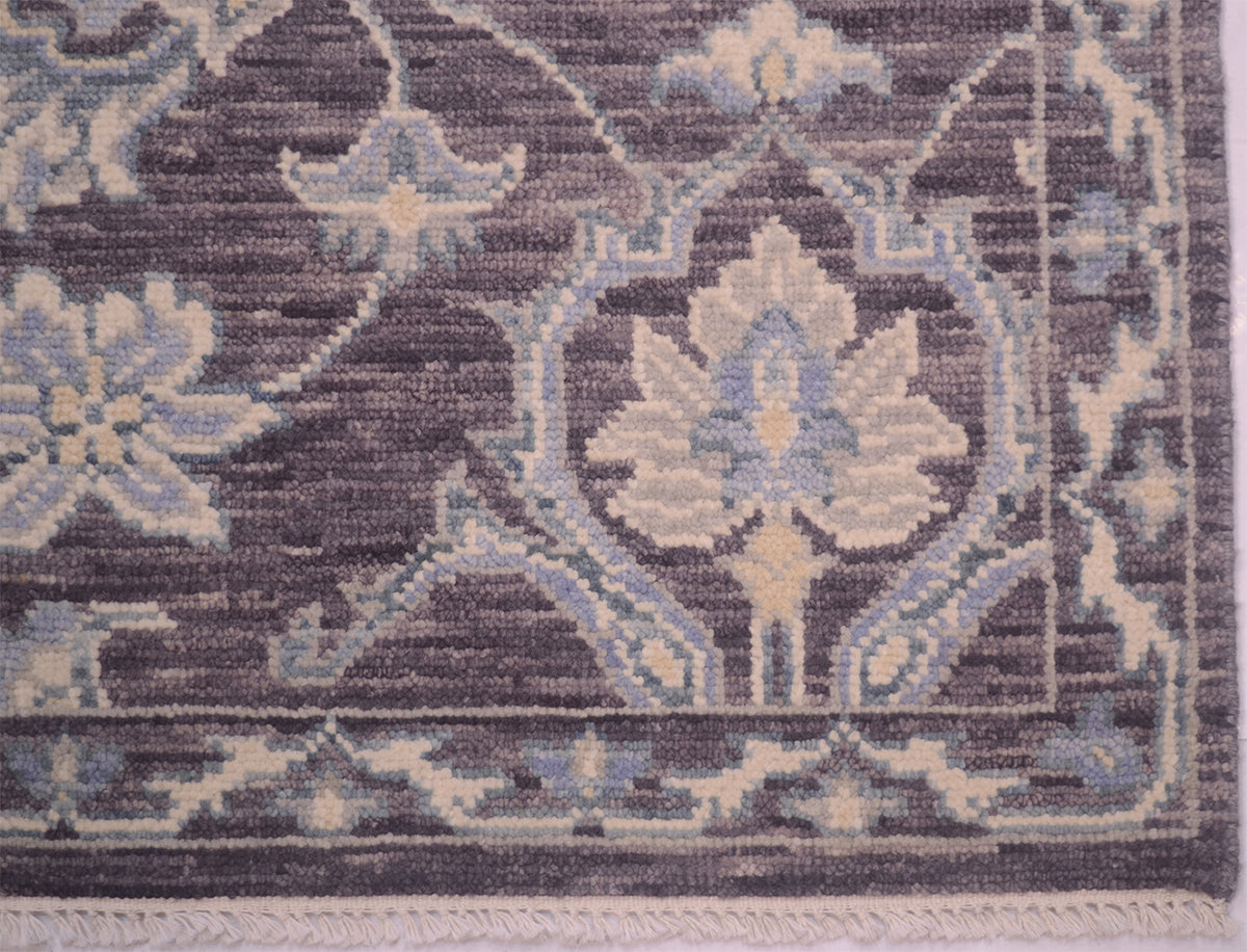 Close-up of a traditional Tonal  rug showing a floral medallion and border design in muted blue, beige, and dark pewter tones.