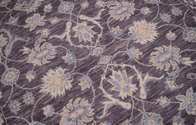 A close-up of a patterned rug featuring a traditional floral design in muted blue, beige, and gray tones on a pewter background.