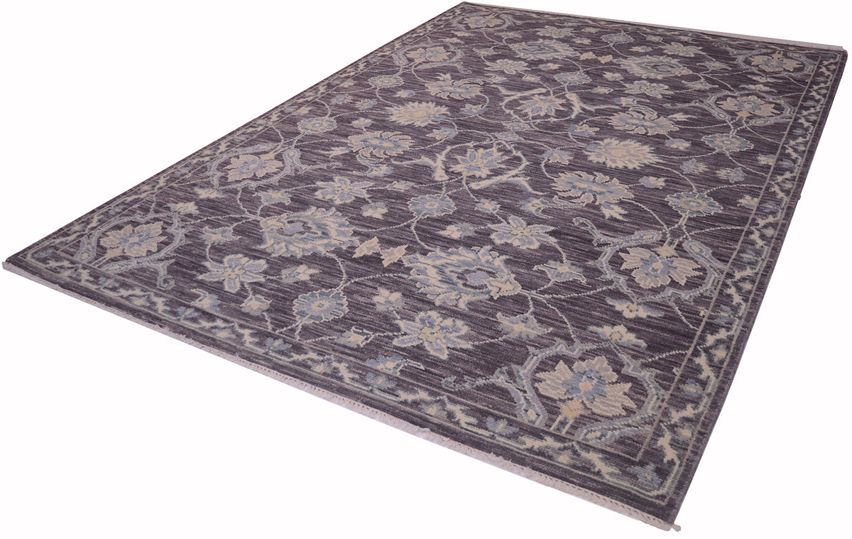 A rectangular Tonal rug with a traditional floral pattern in muted shades of pewter, beige, and light blue, shown from an elevated angle on a white background.