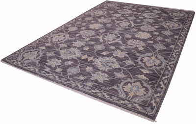 A rectangular Tonal rug with a traditional floral pattern in muted shades of pewter, beige, and light blue, shown from an elevated angle on a white background.