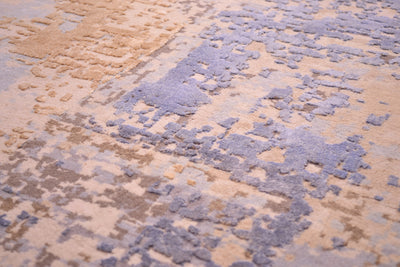 Detail of raised silk areas in handknotted carpet in blue silk and golden silk and handcut artisanally.   Beige  and clay natural coloured wool pile base background.