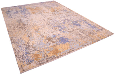 Angled view of handmade Indian carpet with a variety of soft colours and textures. Raised pure silk handcut area of light golden silk with sky blue and light blue.  Dark bronze and beige tones of the main matte areas of wool pile.