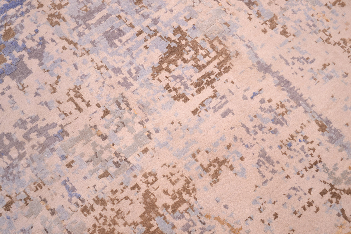 Main focal close up of wool and silk pile of Handknotted Indian Carpet showing areas of natural beige cream wool pile with dark bronze and blue grey. Textural area of raised  pure silk in light and mid blues. 