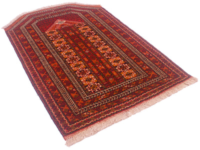 A rectangular Turkoman prayer rug with a traditional geometric pattern in shades of red, orange, and brown, featuring cream-coloured fringe on two short ends, shown on a plain white background.