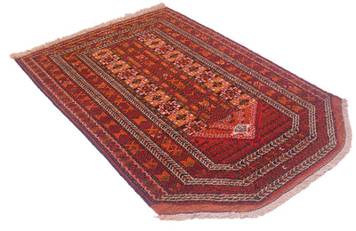 A traditional rectangular Oriental Prayer rug with a complex geometric and floral pattern in shades of red, orange, brown, and beige, featuring fringed edges on a white background.