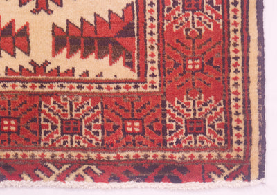 Close-up of a patterned rug mat corner showing cream, red, and dark navy geometric motifs with a fringed edge.