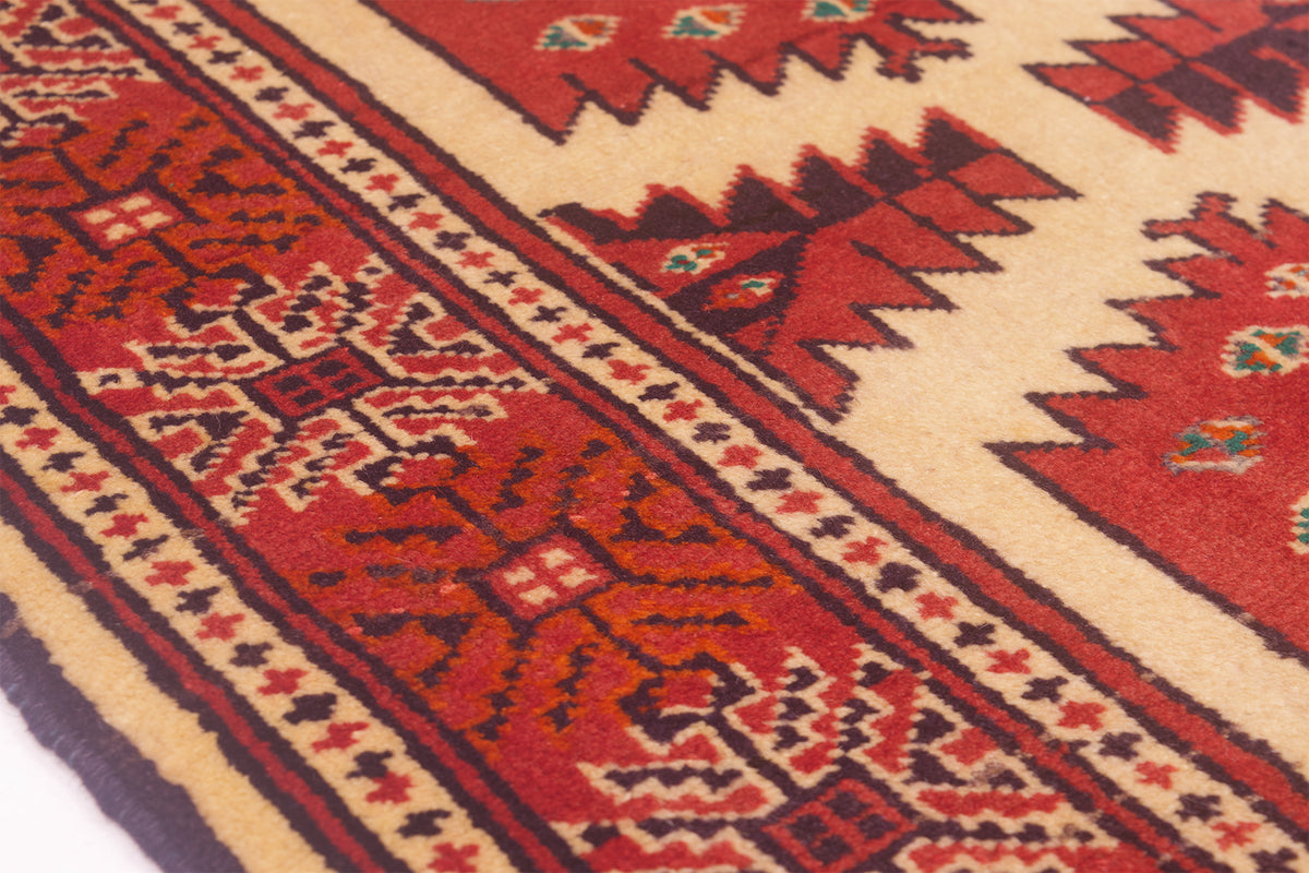 Close-up of a patterned area rug mat with a red and beige geometric design, featuring tribal-style motifs and borders.