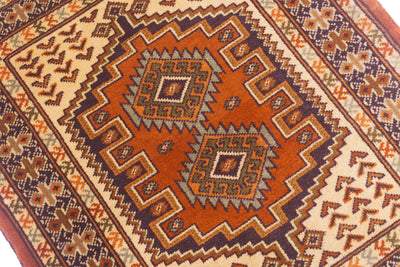 close-up of a traditional geometric patterned rug mat with a warm rust-orange center, cream borders, and dark brown and navy details.