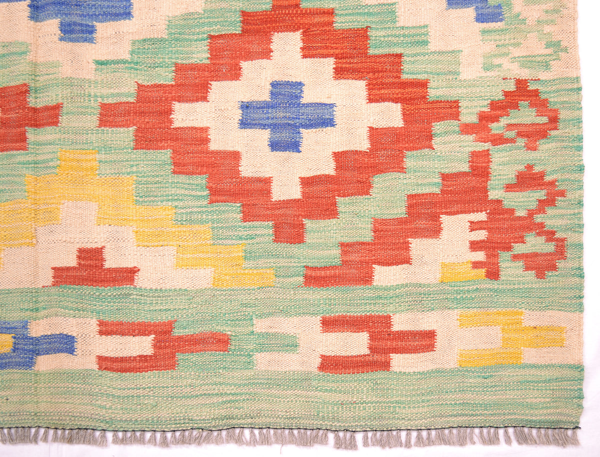Handwoven kilim rug close-up of red central cross motif with fringe border