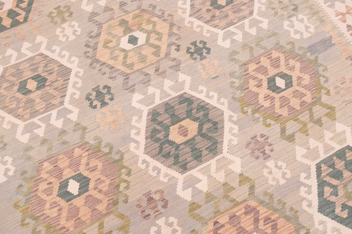 A close-up of a handwoven Large Afghan Kilim with a geometric-style pattern in muted beige, sage green, dusty pink, and cream tones.
