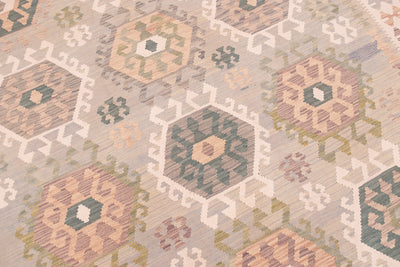A close-up of a handwoven Large Afghan Kilim with a geometric-style pattern in muted beige, sage green, dusty pink, and cream tones.