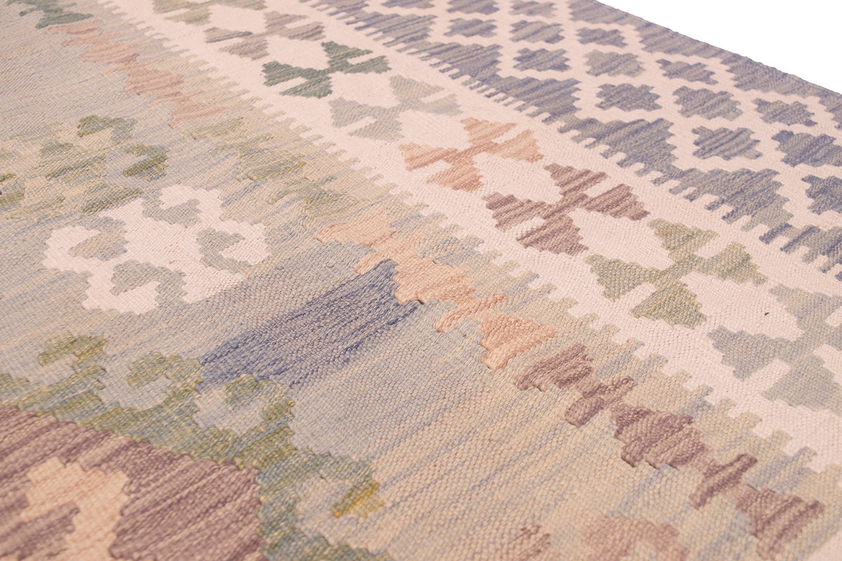 A close-up of a handwoven Afghan Kilim area rug with a geometric and floral pattern in muted beige, grey, blue, green, and brown tones.