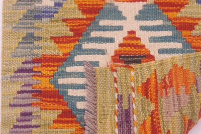 Close-up of a narrow Afghan Kilim Strip with a geometric pattern in cream, blue, orange, yellow, purple, and grey, showing the texture and fringe of the fabric.