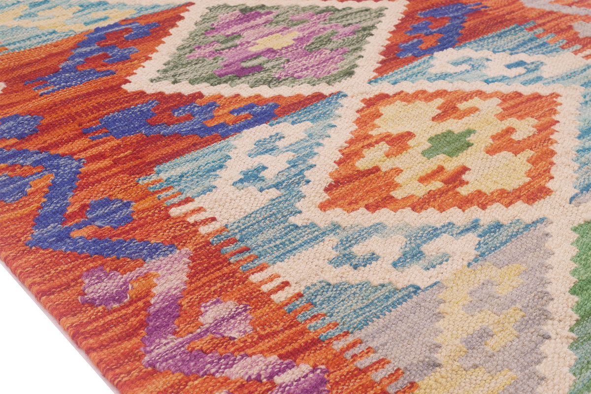 A close-up of a multicolour Afghan Kilim short runner rug with a geometric diamond pattern in orange, blue, purple, green, and cream.