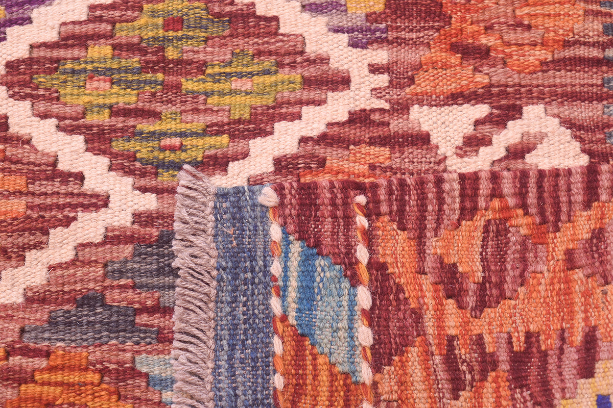 Close-up of handwoven kilim rug motif with red, orange, blue, and white accents.