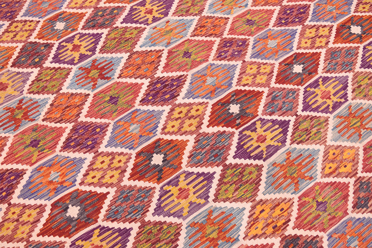 Close-up of handwoven kilim rug with colorful geometric diamonds and border.
