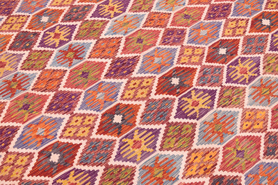 Close-up of handwoven kilim rug with colorful geometric diamonds and border.