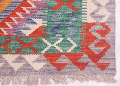 Colorful kilim runner rug corner with diamond pattern and light purple fringe